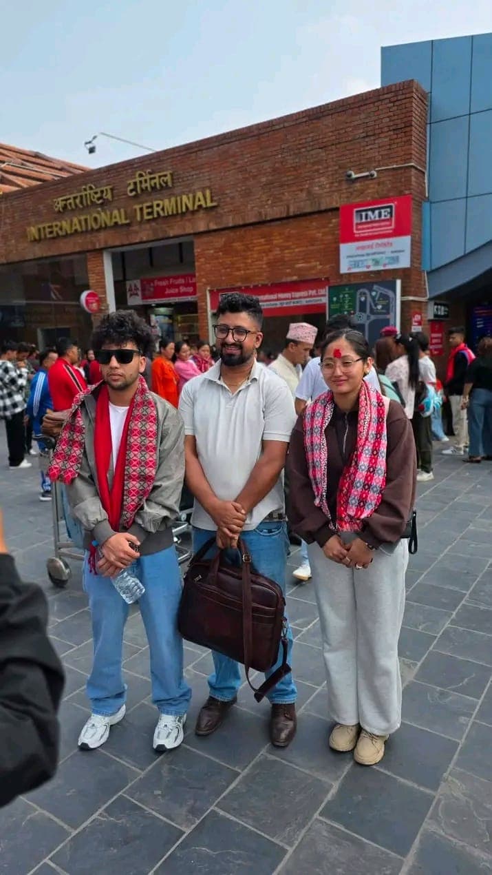 A team member seeing off two students in farewell scarves at the international terminal