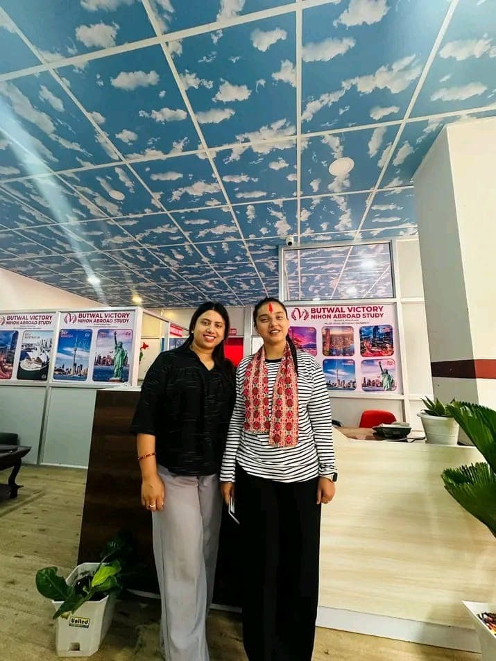 Two women standing at the counselling desk, with study-destination posters behind them