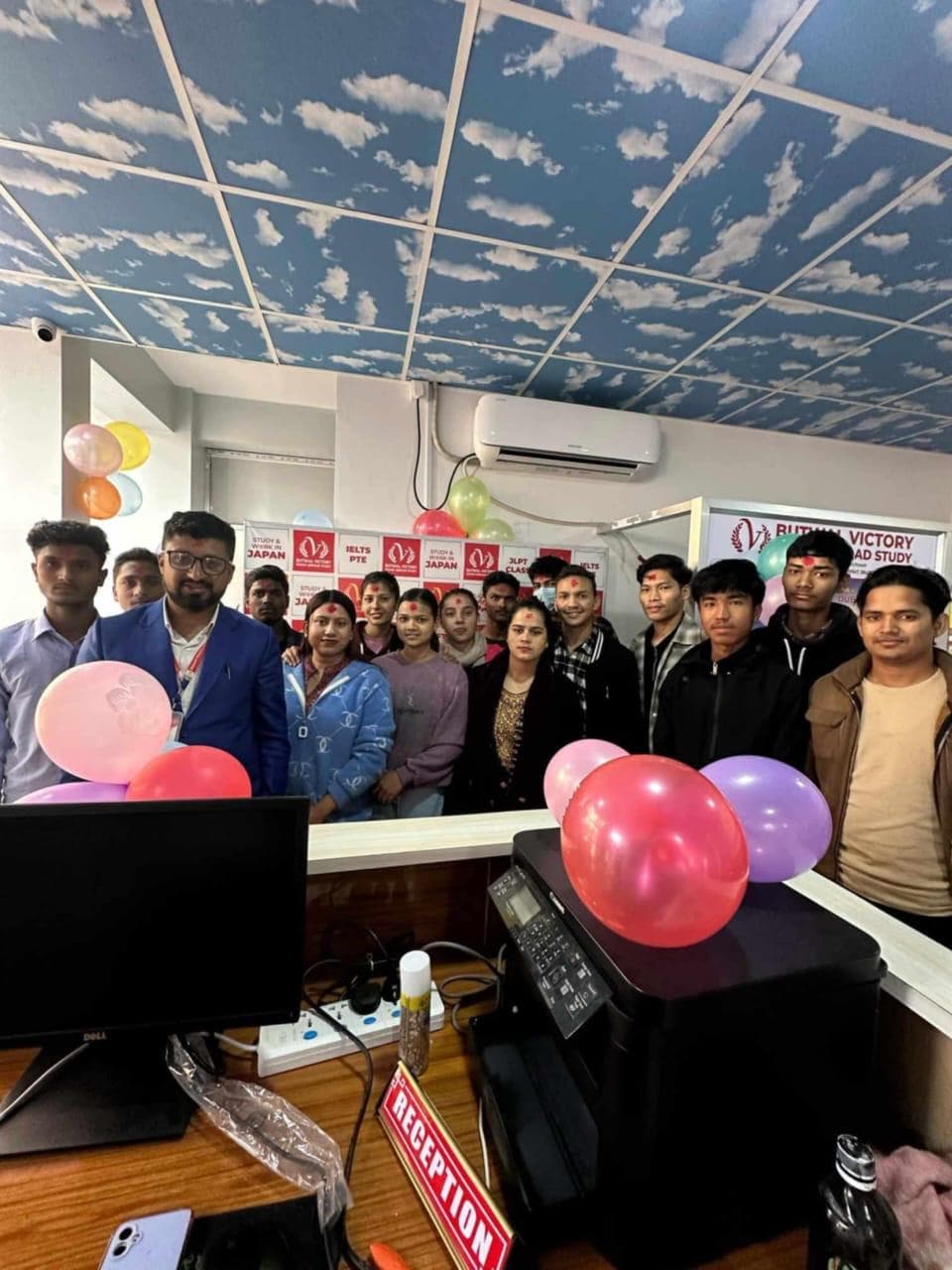 Students and staff standing behind the decorated reception desk at the office