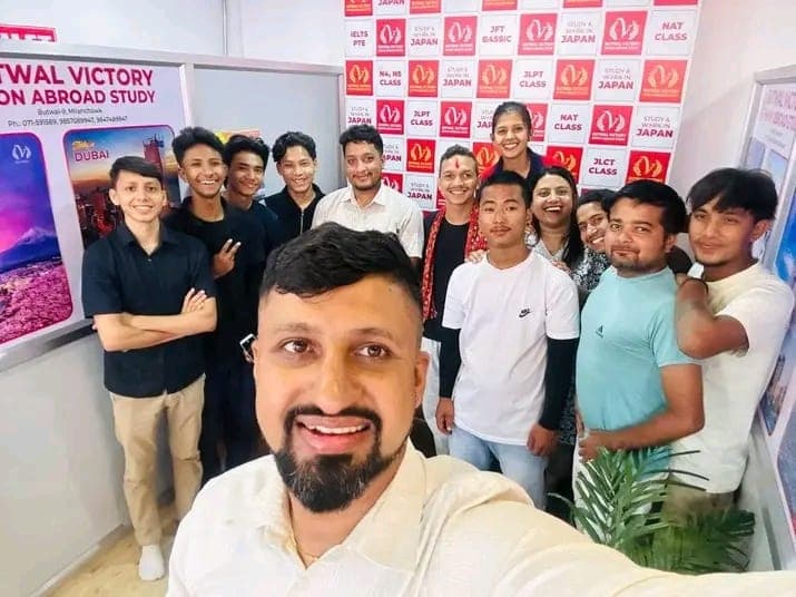 Group selfie of students and staff in front of the language-class notice board