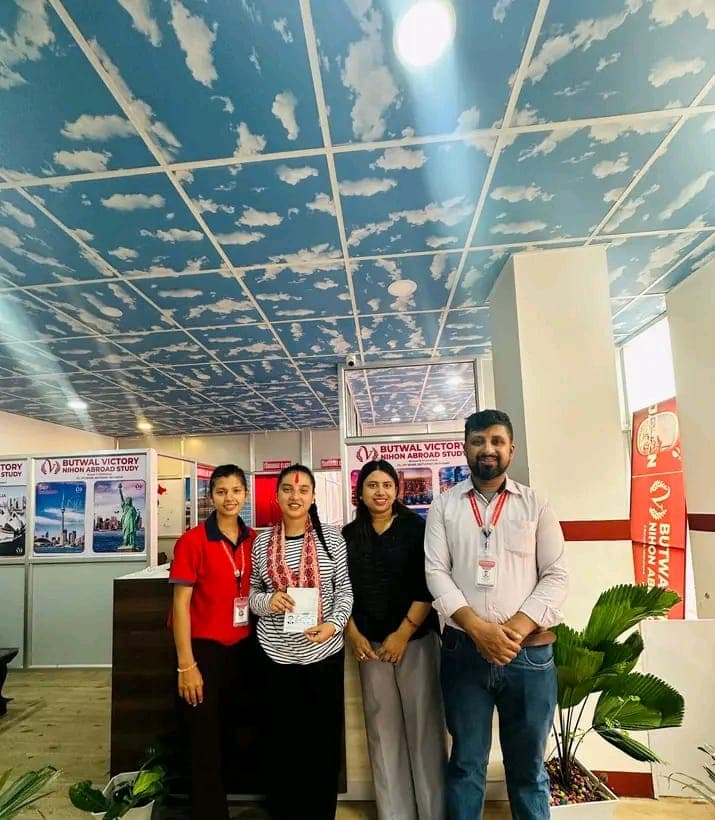 Three team members standing with a student holding her passport inside the office